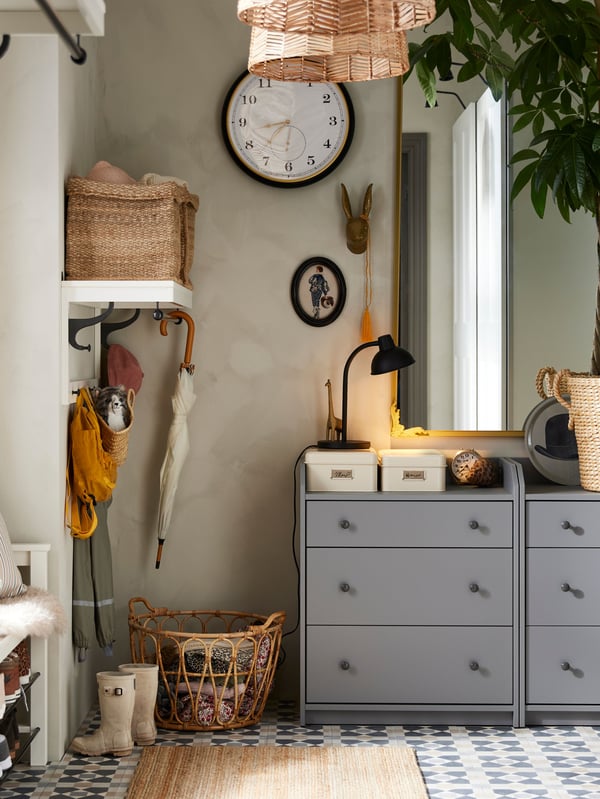 Deux commodes HAUGA grises à 3 tiroirs dans un entrée avec un tapis de LOHALS au sol dans façade, un miroir et une horloge au-dessus.