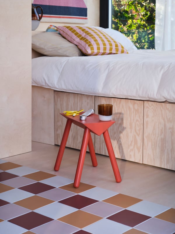An orange-red/stained OMMJÄNGE stool in the bedroom