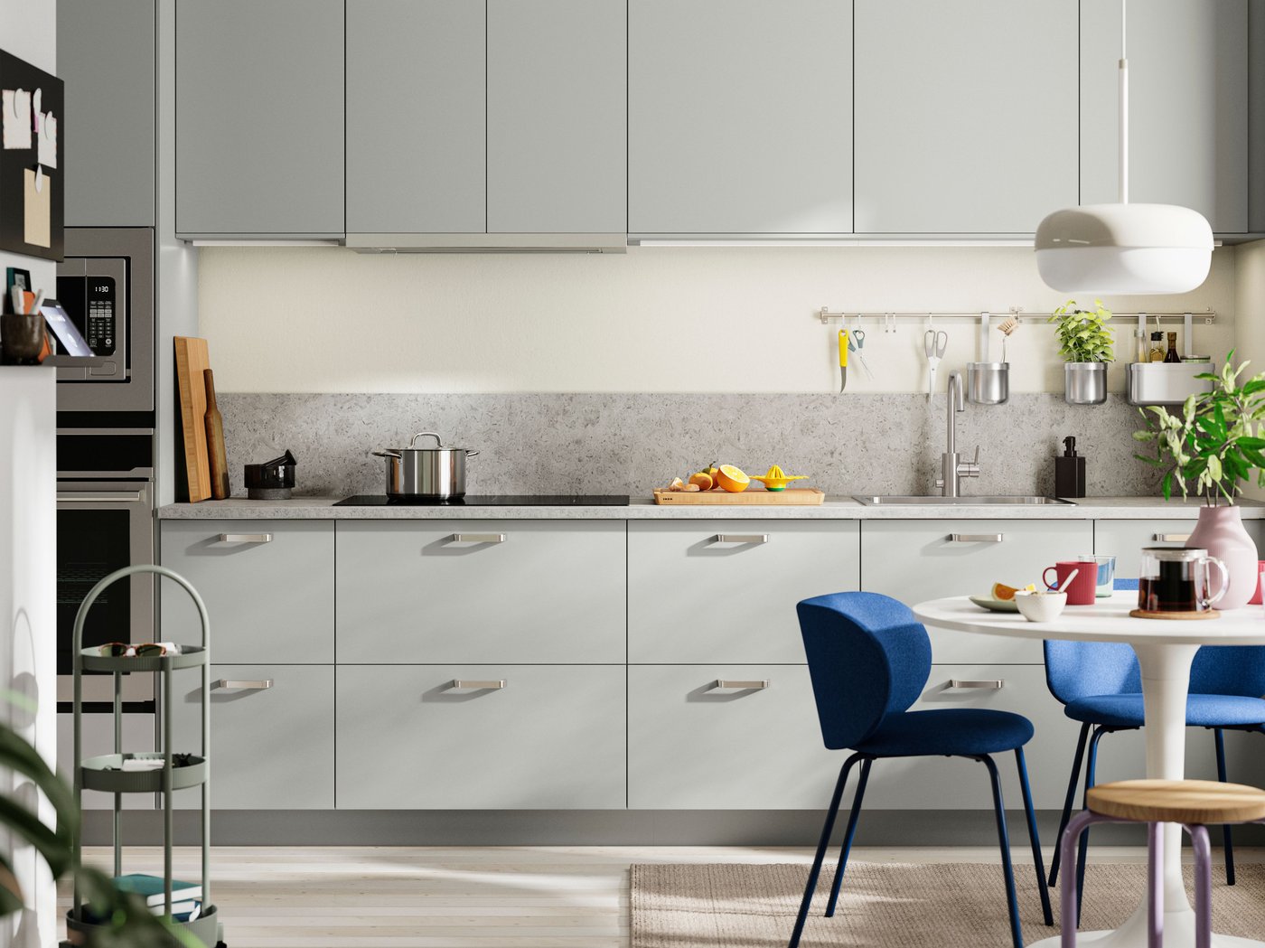 HAVSTORP light grey kitchen fronts with a grey worktop, blue chairs around a white dining table, and potted plants.