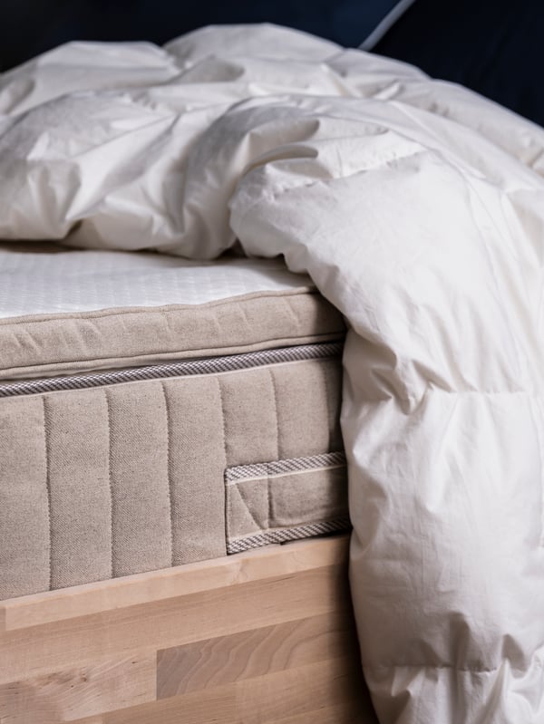 Eine FJÄLLARNIKA Decke auf einer Matratze mit Matratzenauflage auf einem Bett