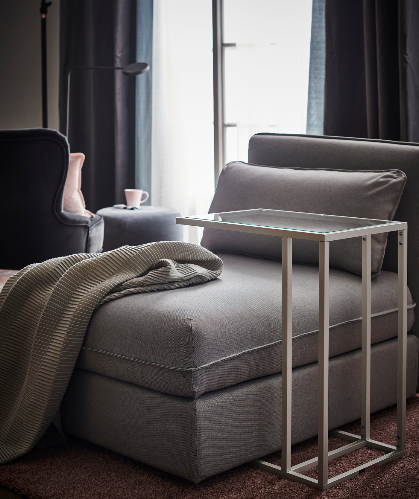A gray chaise longue with a white laptop holder for the sofa