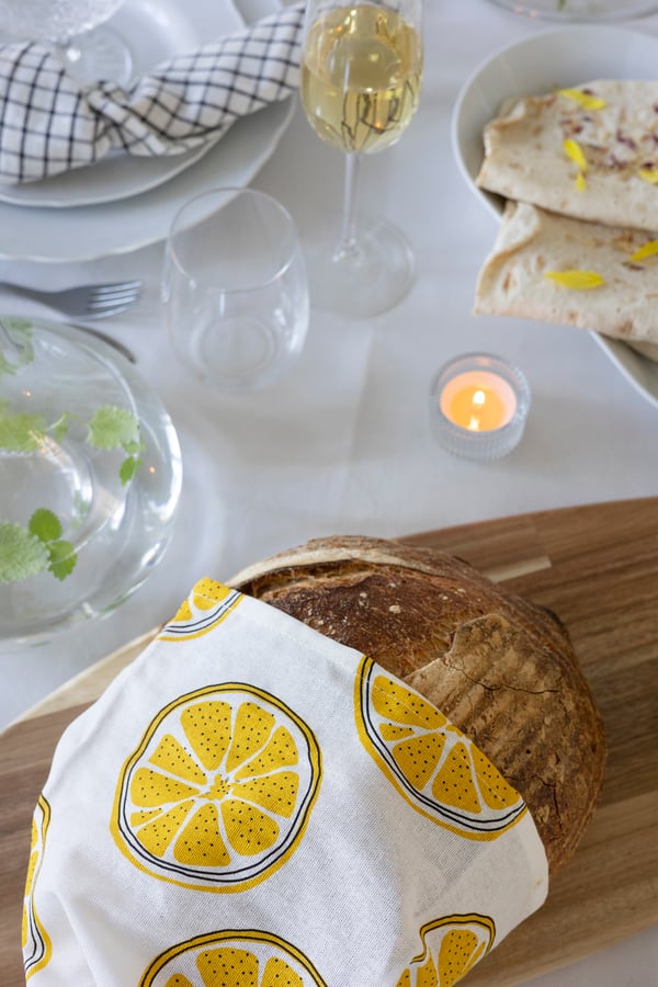 Et brød på et skærebræt med et viskestykke over med citroner på.