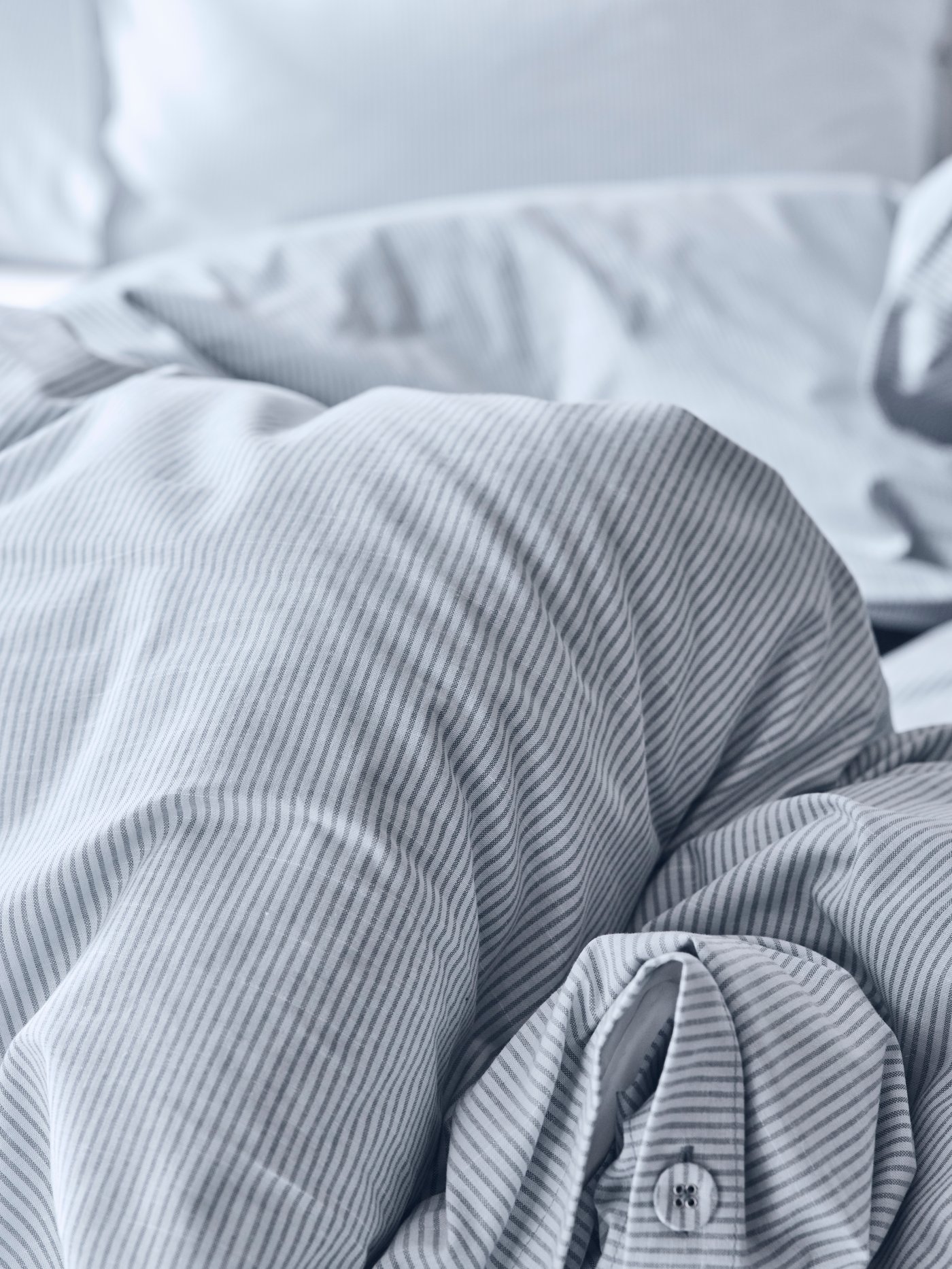 Un plumón blanco con azul doblado sobre una cama.