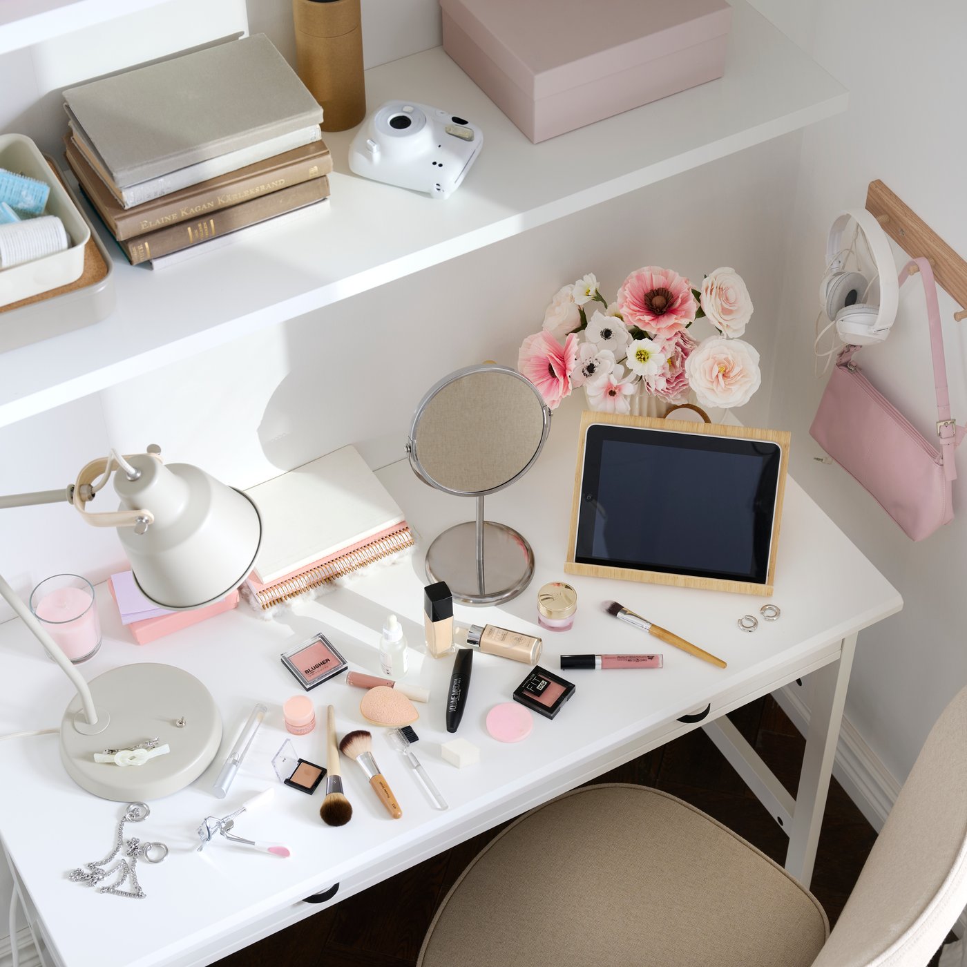 Una zona de estudio con un escritorio BRYTNING de material blanco sobre el que hay cosméticos y una tablet rodeados de flores.