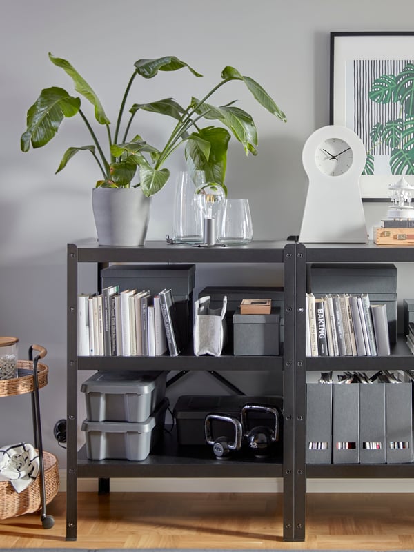 Two black and sturdy BROR shelving units that hold lots of decorative items, books, magazine files, kettlebells and more.