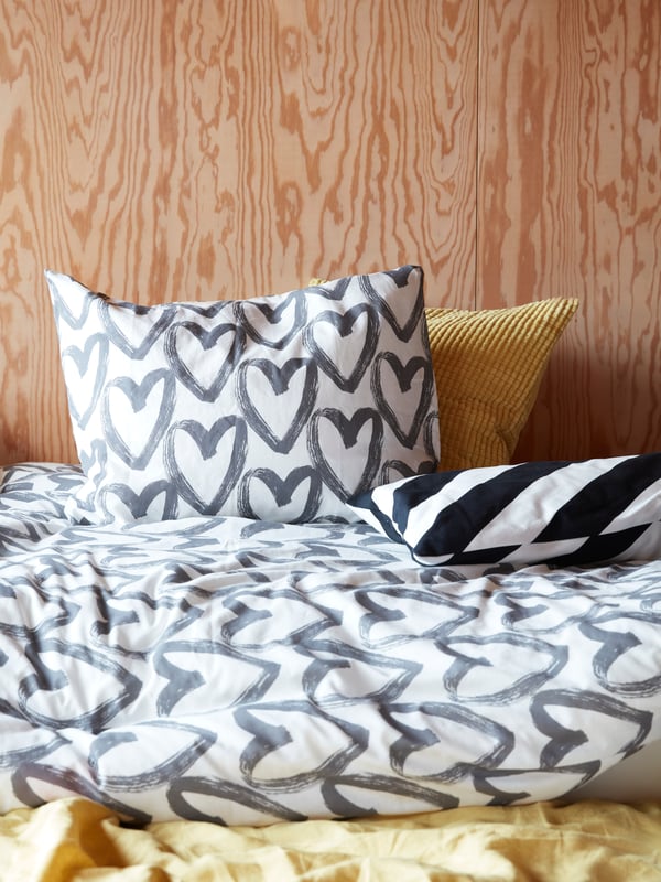 Ein Bett bedeckt mit einer knallbunten Auswahl von Bettdecken, Kissen und anderen Textilien