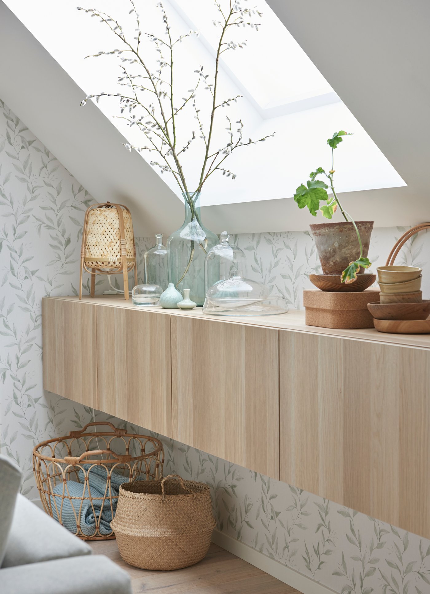 A wall-mounted BESTÅ cabinet with oak veneer doors in a bedroom with sloped ceilings.