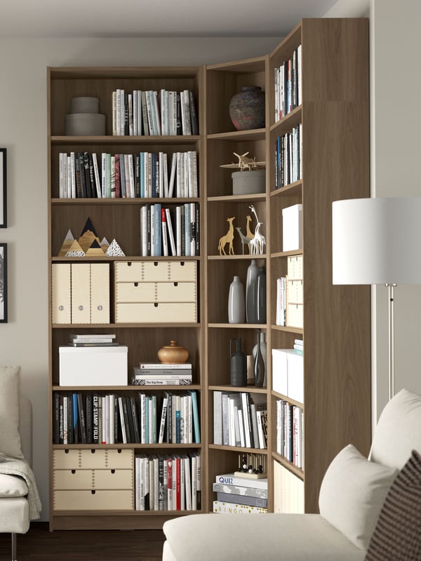 Un librero BILLY efecto madera en una sala con muebles beige.