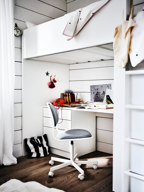 Une chaise ÖRFJÄLL devant un bureau blanc sous un lit mezzanine SMÅSTAD dans une chambre blanche avec un sol en bois foncé.