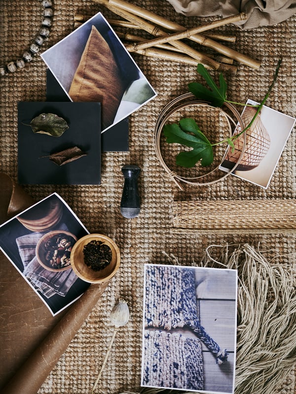 A coarsely woven rug with several printed pictures plus a variety of raw materials including leaves and wool.
