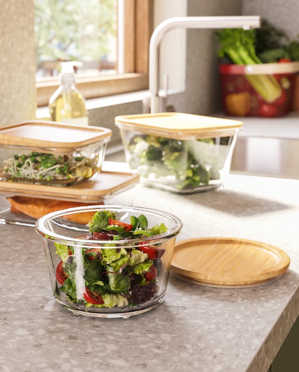 IKEA 365+ glass food containers with bamboo lids filled with different foodstuffs, and wine glasses in a cosy setting.