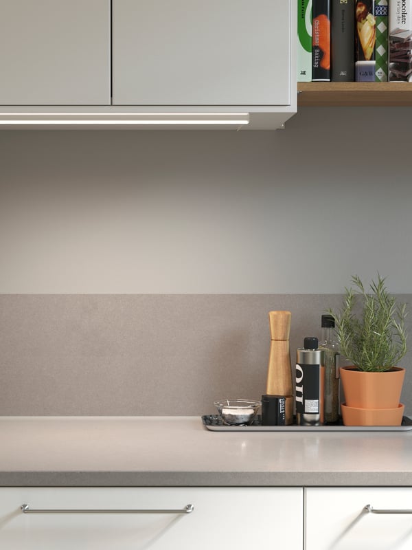 A light grey laminate kitchen backsplash with a mineral effect and a matching worktop below a wall-mounted cabinet.