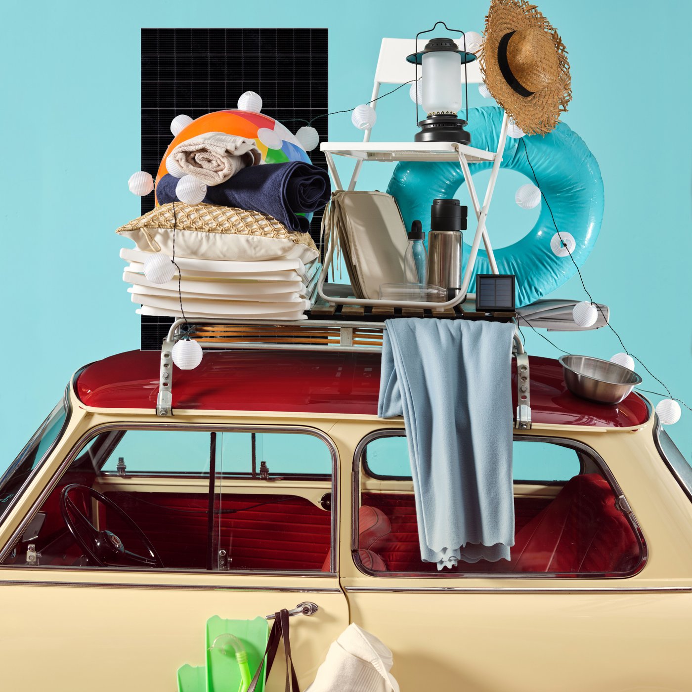 Une voiture rétro remplie à ras bord d'articles IKEA colorés indispensables pour le camping et la plage, allant de la vaisselle aux textiles en passant par une lampe portable, crée une ambiance estivale pleine de gaieté.