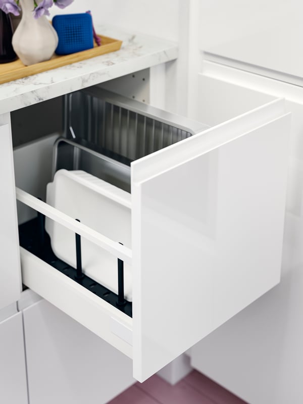 Open drawer with a VOXTORP kitchen fronts in high-gloss white, with an oven dish inside.