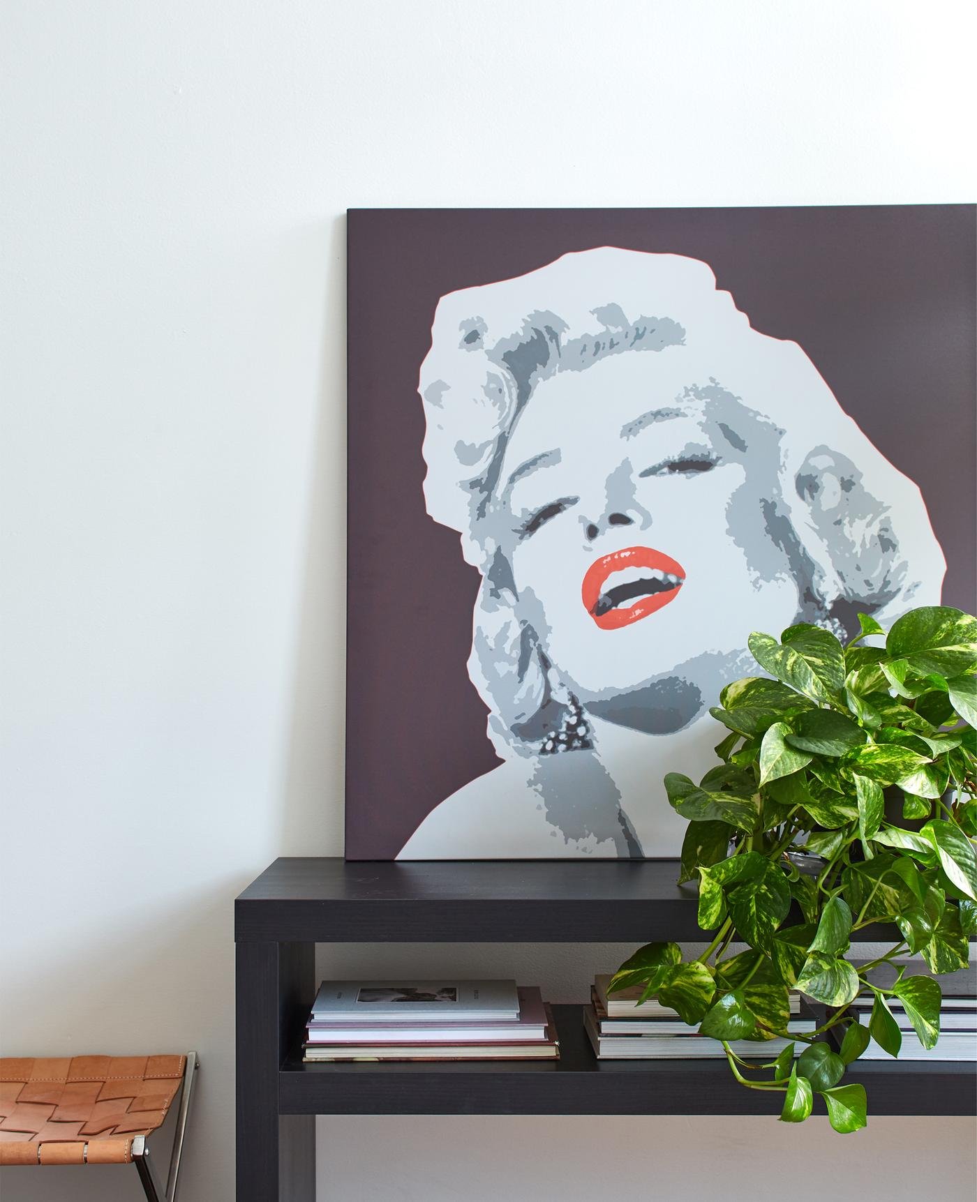 Ein Portrait von Marilyn Monroe hinter LACK Couchtisch schwarzbraun vor einer weißen Wand.