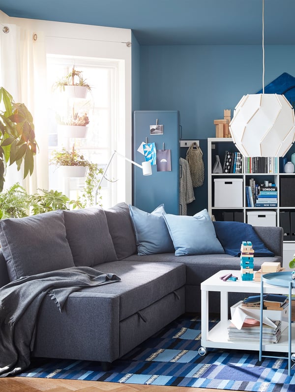 A grey FRIHETEN sofa bed in a blue living room.