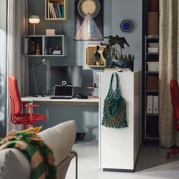 A contemporary office with pale blue walls, wall-mounted EKET wall shelves and a SMÖRKULL office chair in Gräsnäs red.