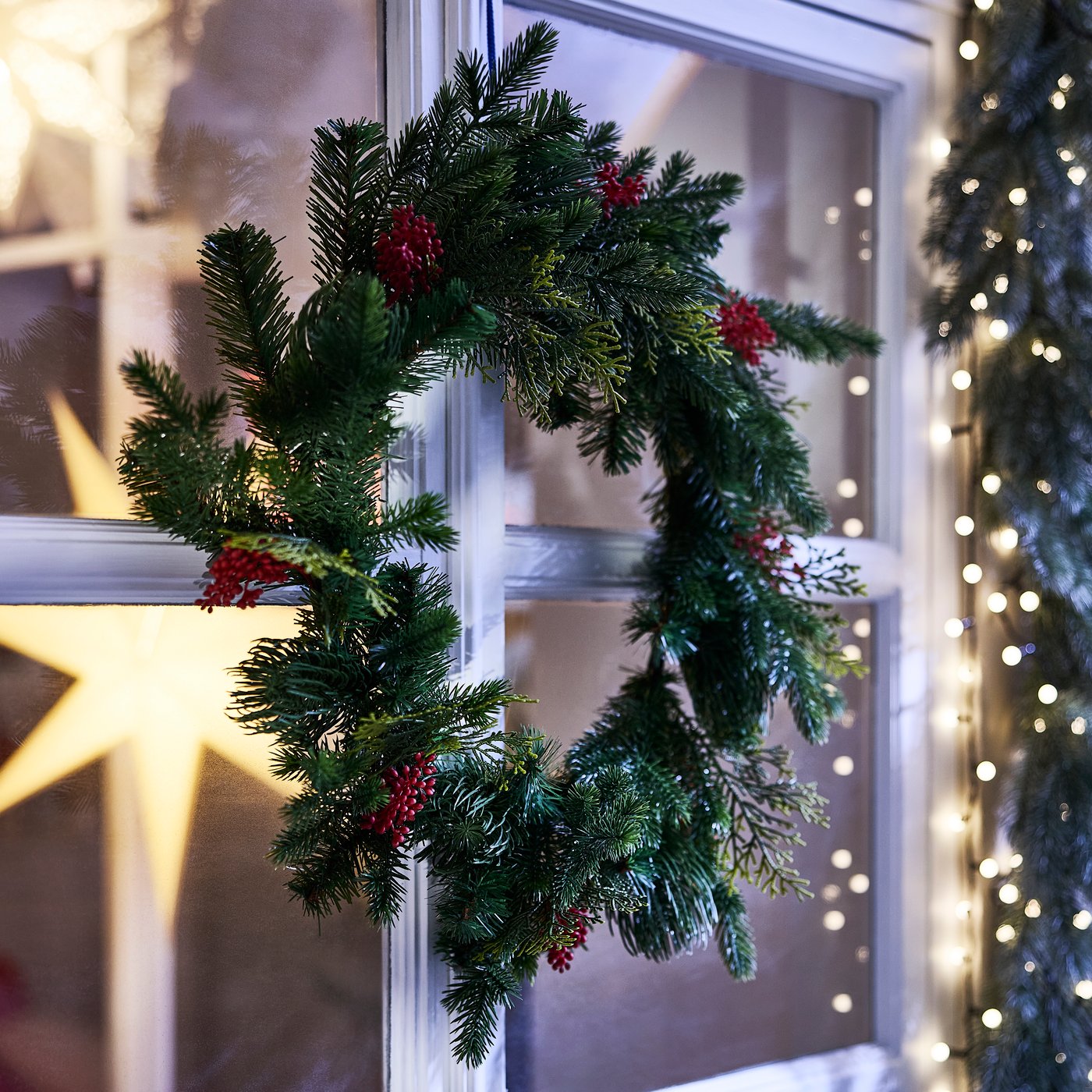 A Christmas garland is hanging in the front window