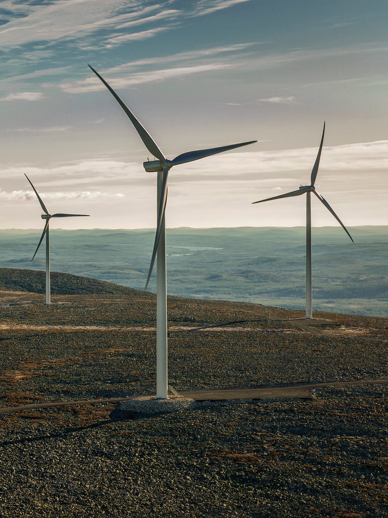 Nekoliko visokih vetroturbina u brdovitom krajoliku koristi energiju vetra pod vedrim nebom.
