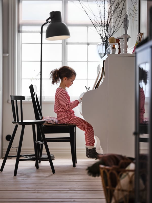 Silla INGOLF negra donde una niña toca piano.
