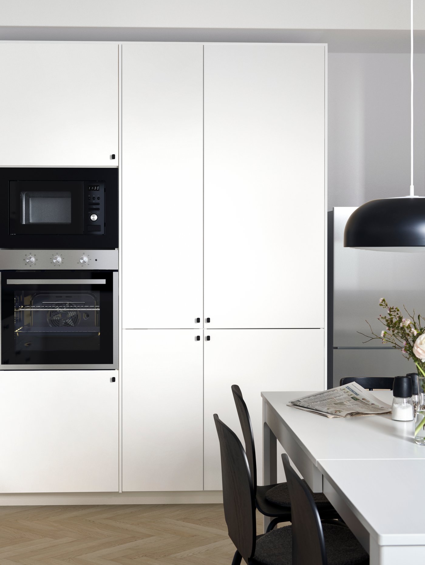Modern white kitchen with simple black knobs and dining room with a white table and black dining chairs