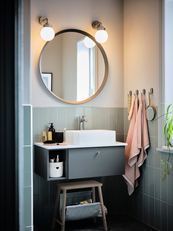 The washbasin corner of a bathroom, with a GODMORGON/TOLKEN cabinet combination and a round, dark-grey LANGESUND mirror.