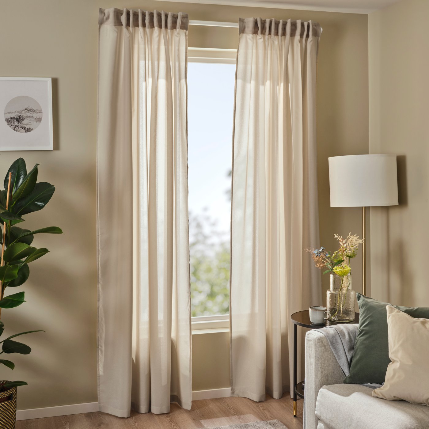 Ein Paar beige ROSENROBINIA Vorhänge mit Kräuselband hängen vor einem Wohnzimmerfenster neben einem beigen Sofa.