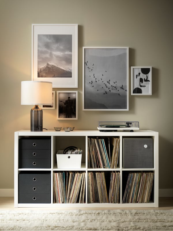A TONVIS table lamp and a record player standing on a white KALLAX shelving unit. Framed art hangs on the wall above.