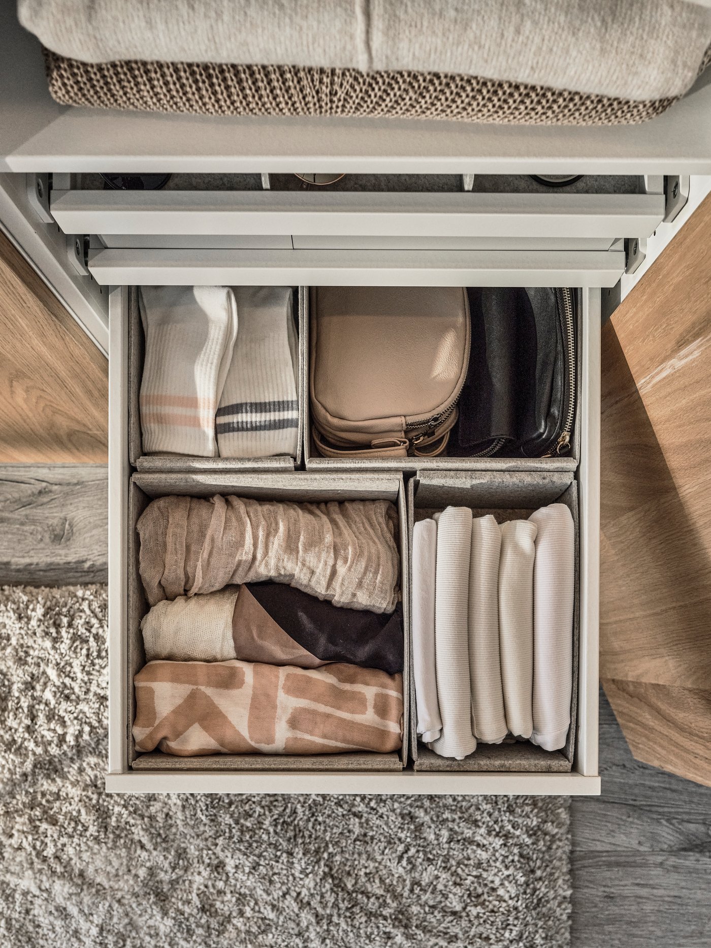 An overhead view of a grey KOMPLEMENT drawer with four grey KOMPLEMENT storage boxes inside holding small clothing items.