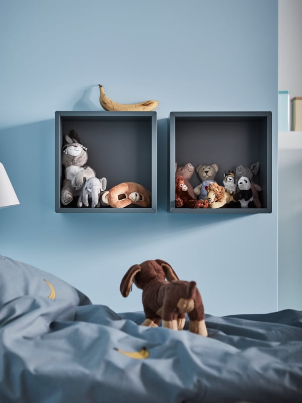 The top of a loft bed by a window with bedding that’s covered in white bed linen with a black spotted detail and a red trim.