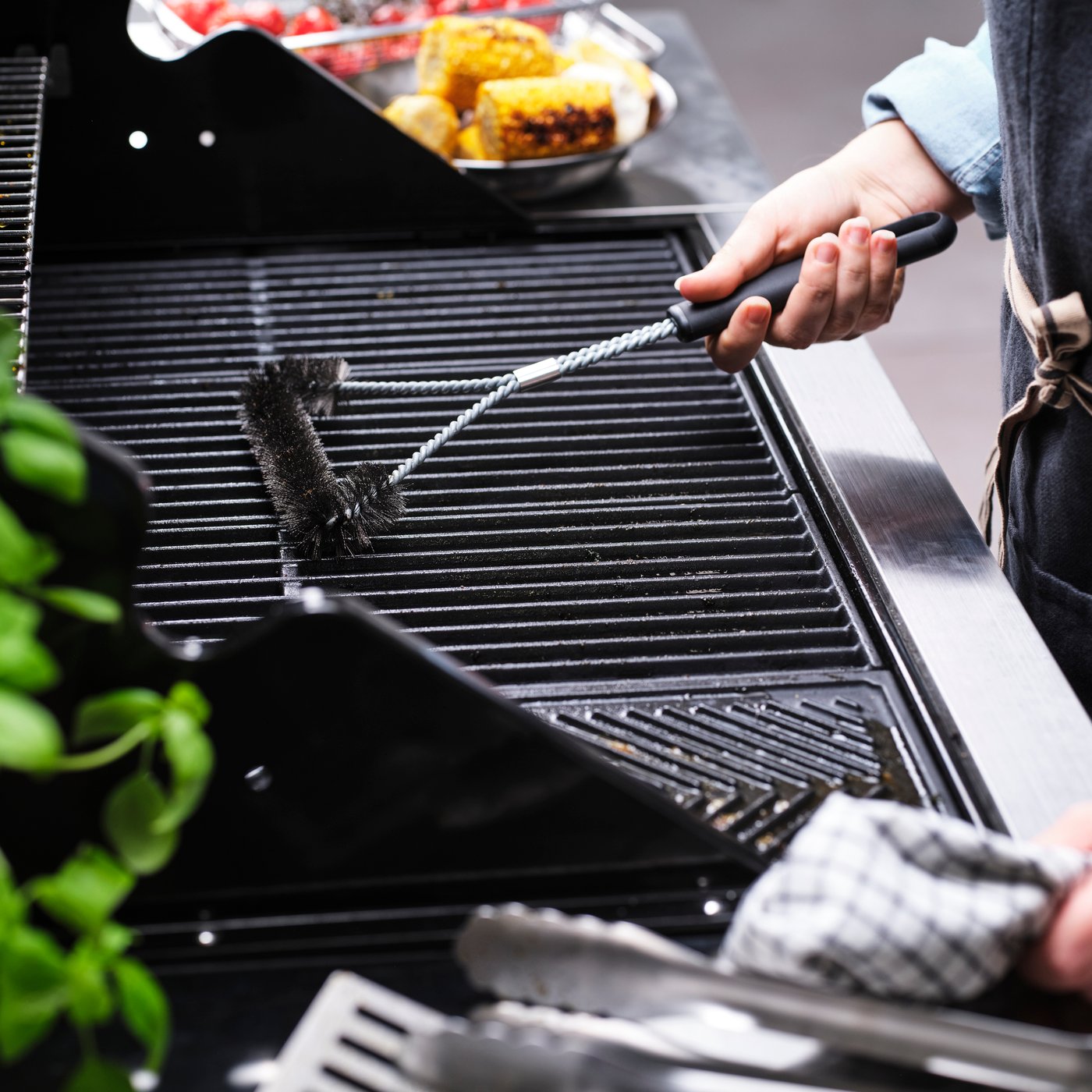 A stainless steel/black GRILLTIDER barbecue grill cleaning brush outside