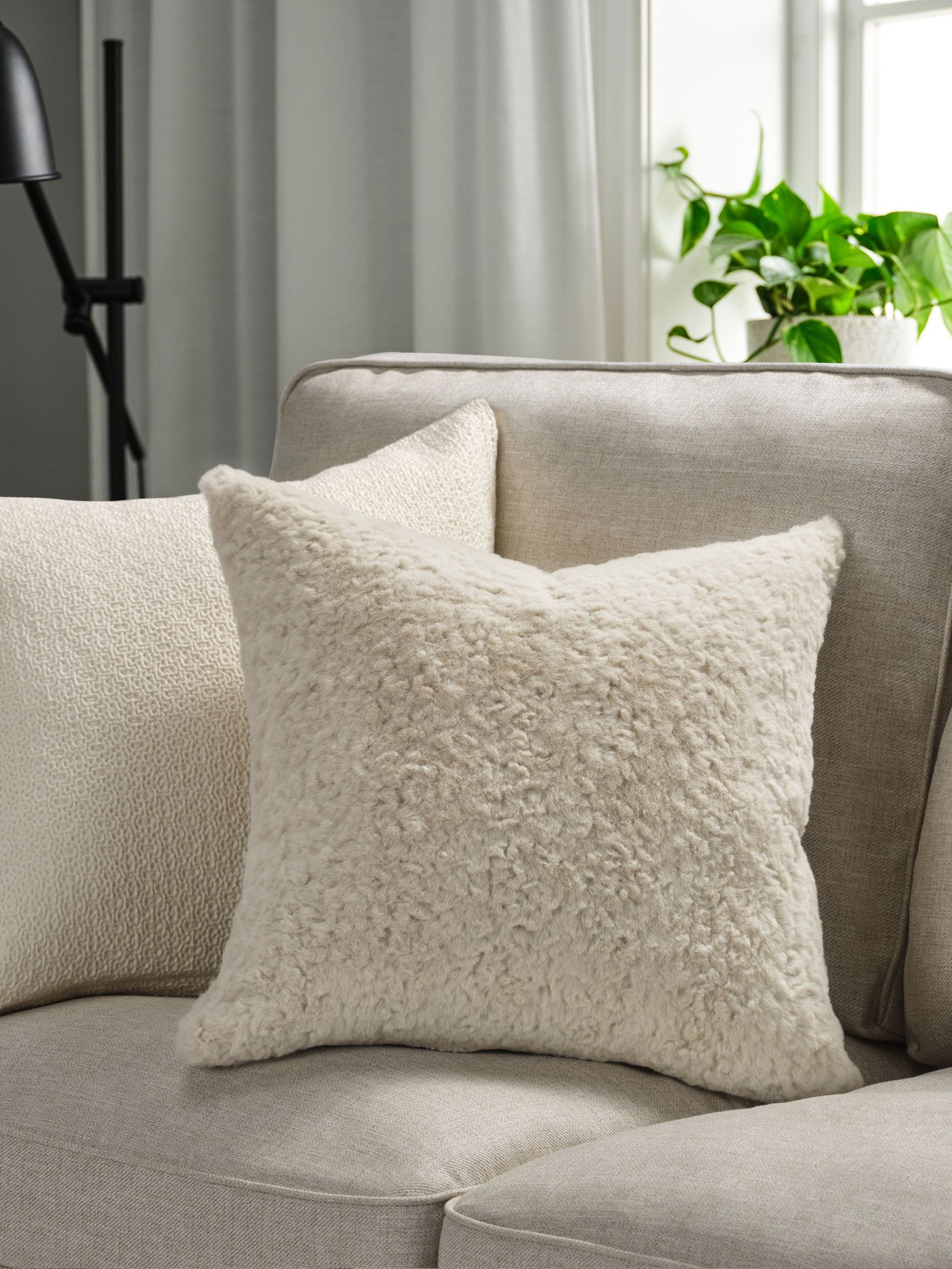 Een beige NÄTNÄVA-kussenhoes in de woonkamer.