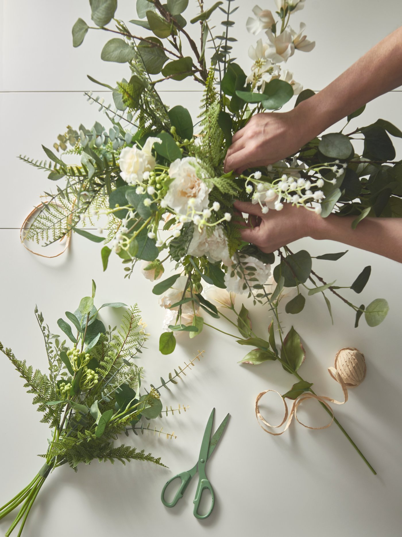 A desconstructed flower arrangement is being trimmed, a pair of green scissors lay open beside.