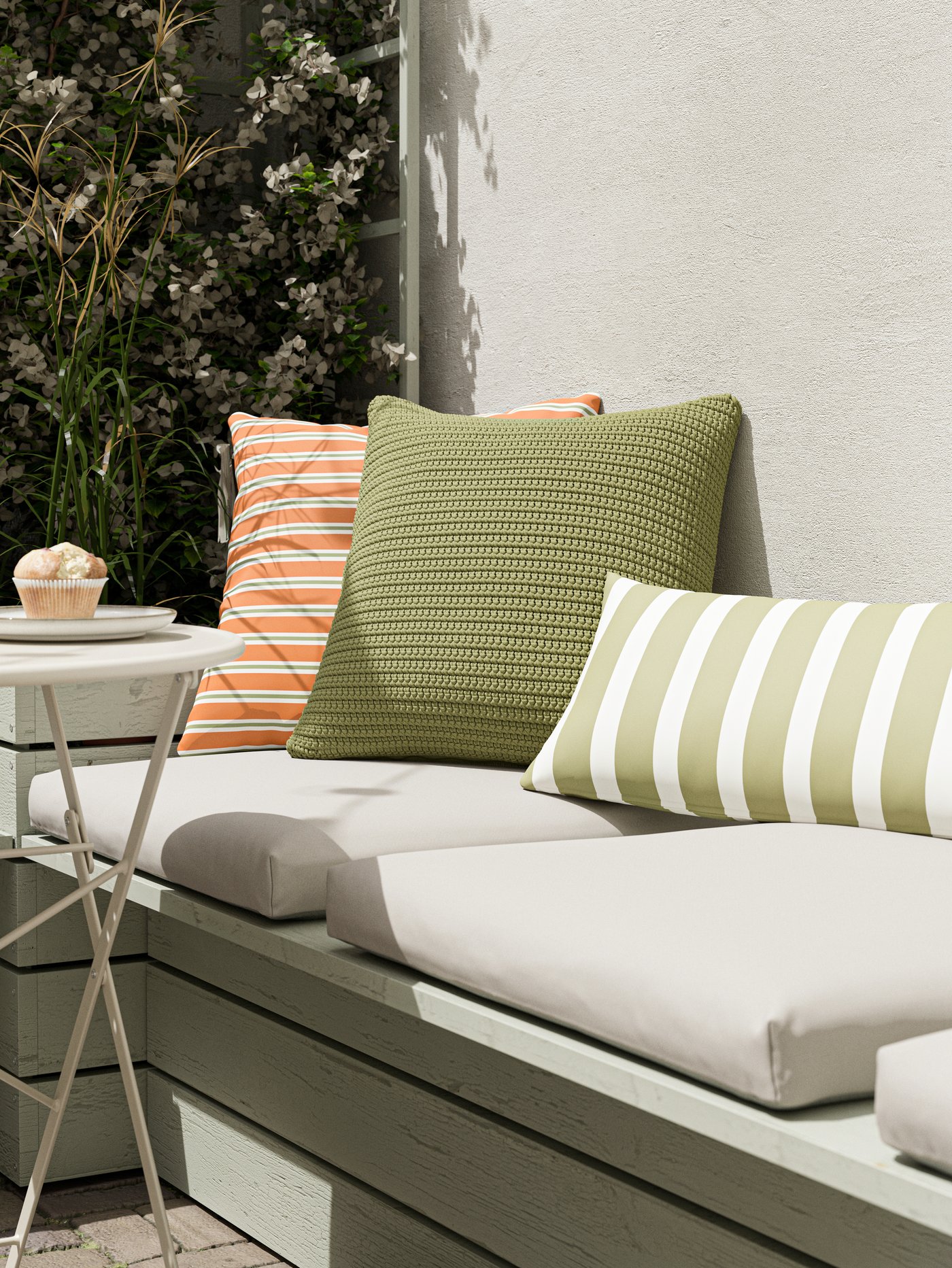 En un balcpon hay un sofá con una variedad de cojines de terraza IKEA.