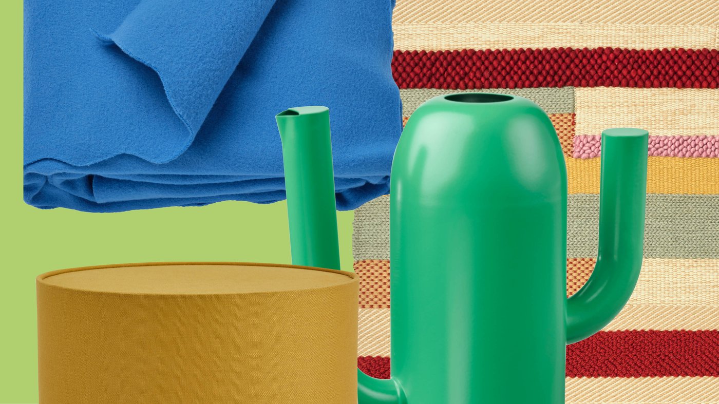 Un mélange ludique composé d'un plaid bleu vif, d'un tapis tissé coloré, d'un abat-jour cylindrique et d'un vase IKEA vert vif crée une atmosphère vivante et joyeuse.

