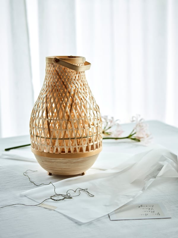 A rattan MISTERHULT  lamp on white tablecloth.