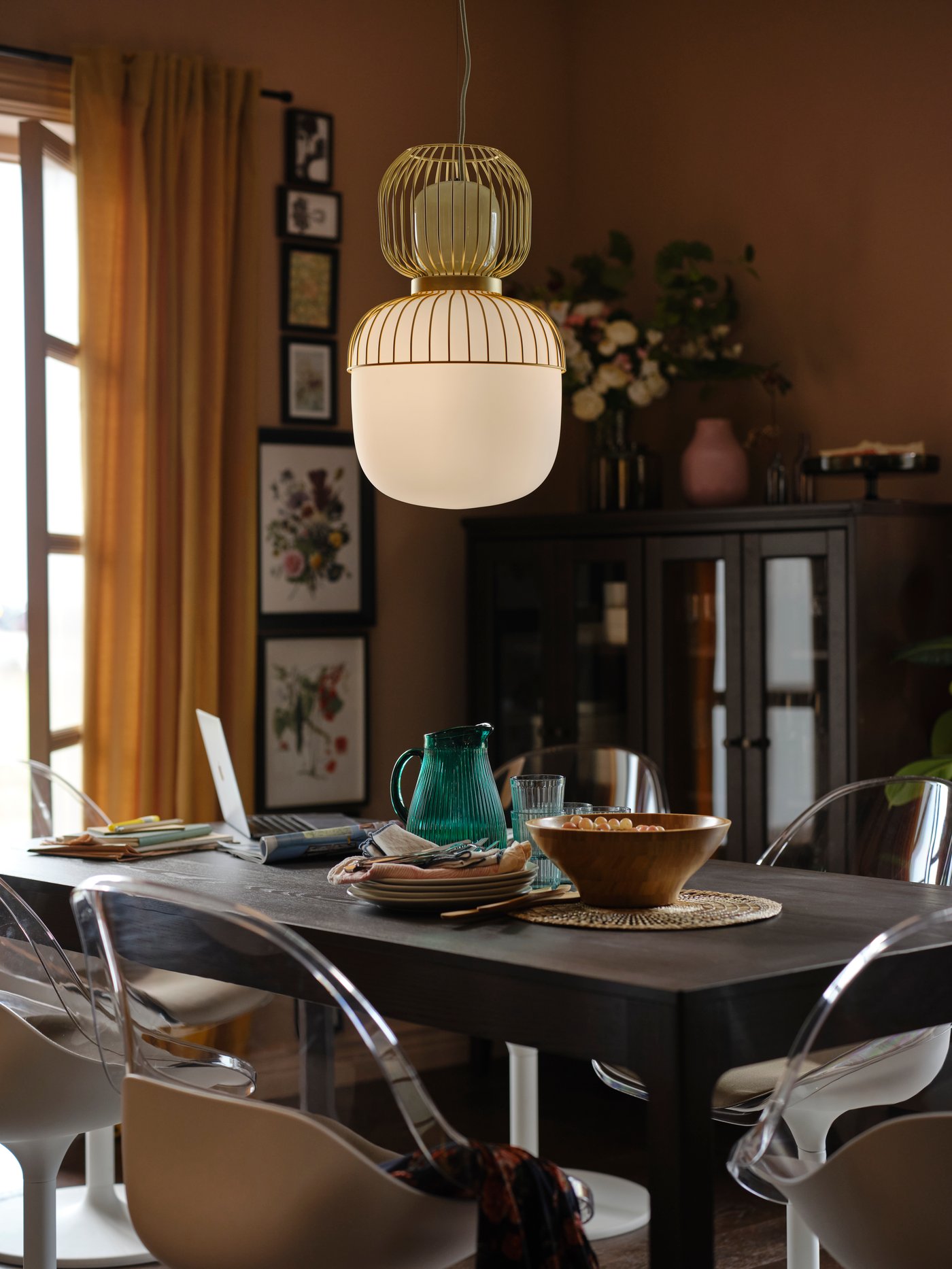 A white/light green glass/gold effect metal PILBLIXT pendant lamp over a dark brown extendable table with swivel chairs.