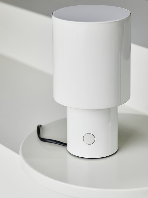Close up of a white SPETSBOJ table lamp on a white plastic surface.