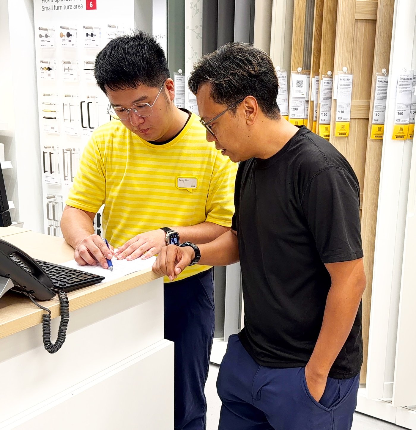 An IKEA co-worker bedroom specialist in the PAX planning station is attending to a customer in the store 