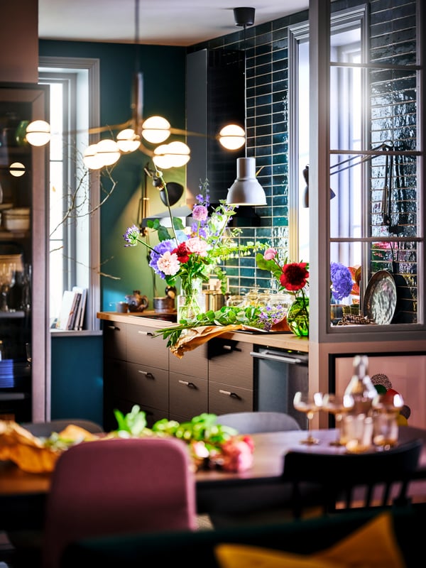 A kitchen with SEKTION cabinets and SÄLJAN oak effect laminate counter-top, a STORSLINGA chandelier and a flower agreement.