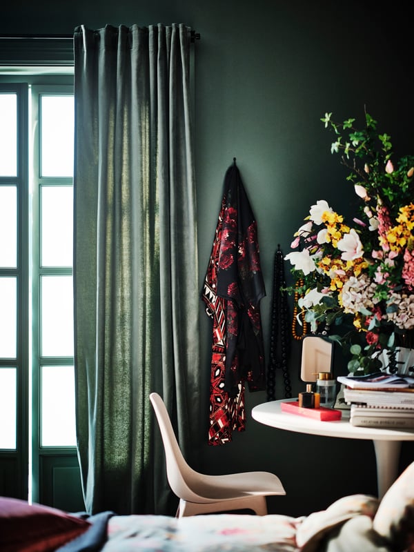 A white/white DOCKSTA table and an ODGER chair next to a window with a grey-green SANELA room darkening curtain.