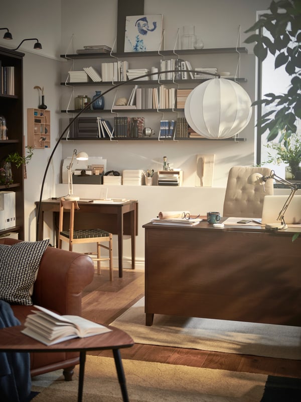 Ein Büro mit schwarzen Wandboards, einem großen Schreibtisch und einem Bücherregal.