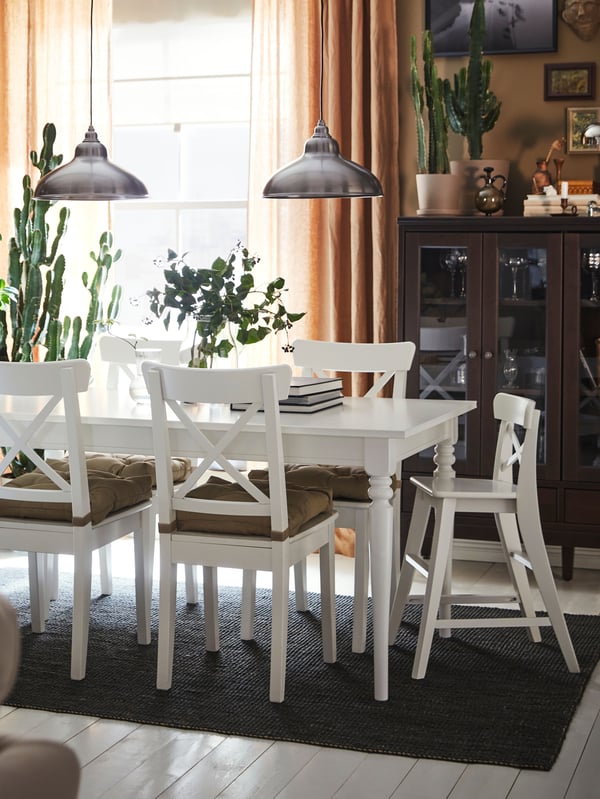 A white INGATORP extendable table, four INGOLF chairs and an INGOLF junior chair stand in a traditional-style dining area.