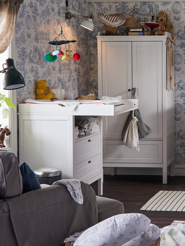 A SUNDVIK changing table stands in a traditional-style children’s room next to a window and near a SUNDVIK wardrobe.