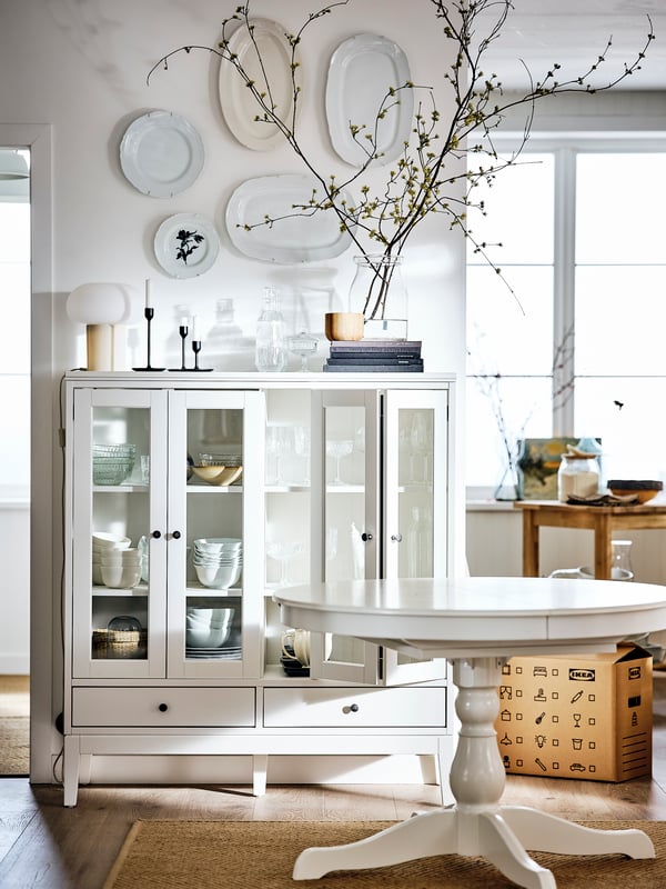 A white dining room containing an IDANÄS glass-door cabinet with plates on the wall above and an INGATORP extendable table.