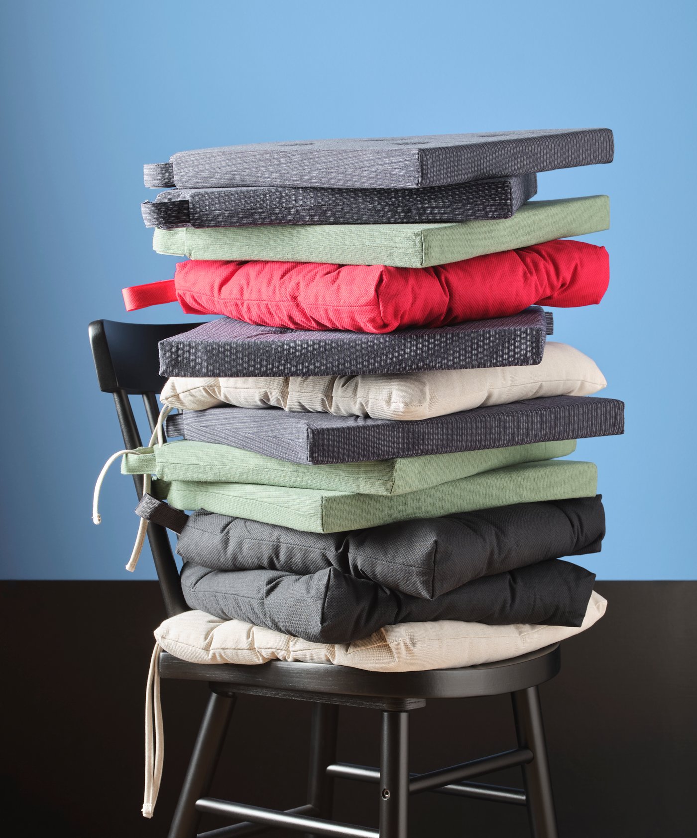 A black chair with a stack of chair cushions in the dining room.