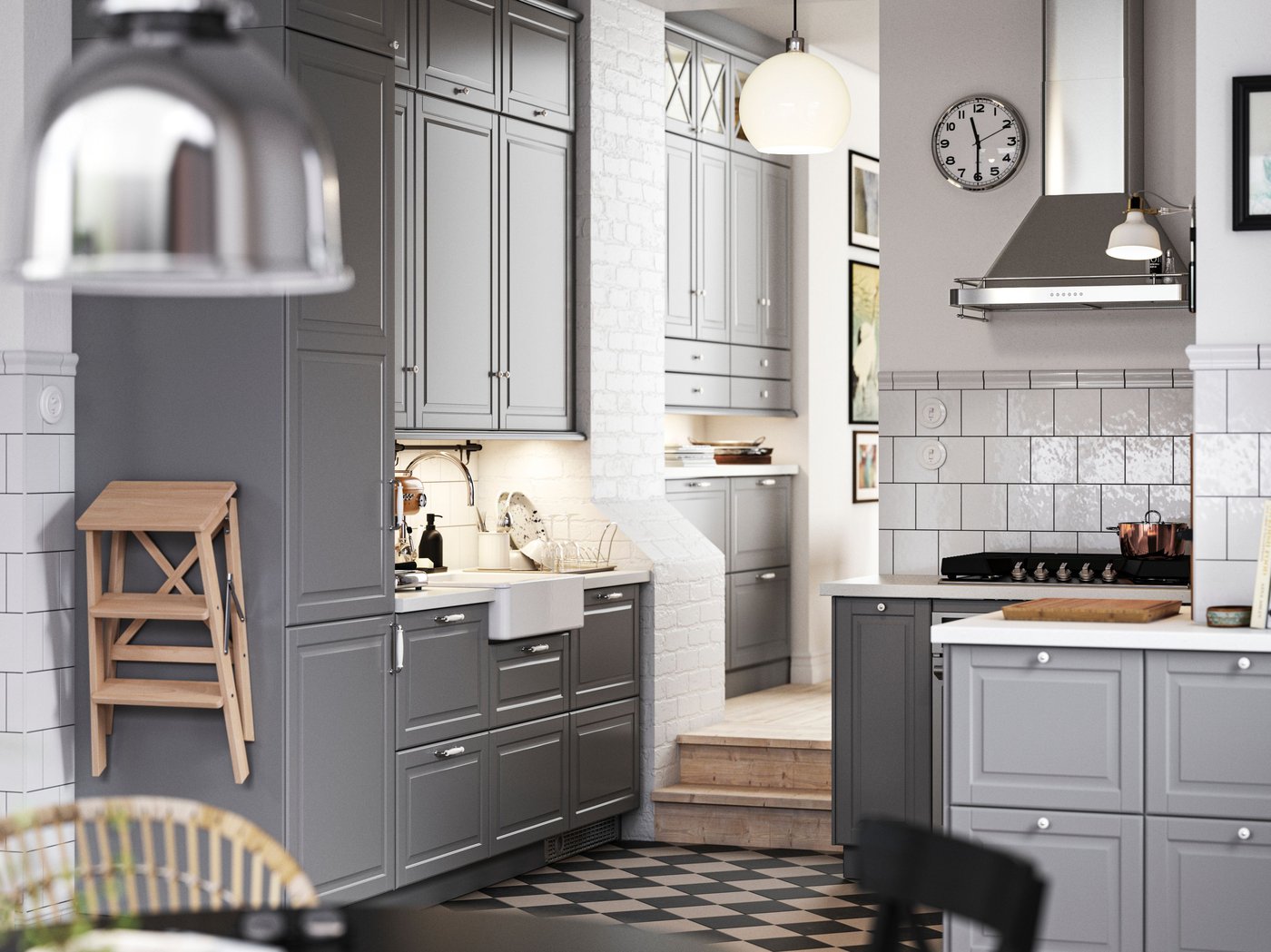 A traditional kitchen with a chequered floor, grey BODBYN kitchen fronts and white/light grey stone effect/laminate worktops.