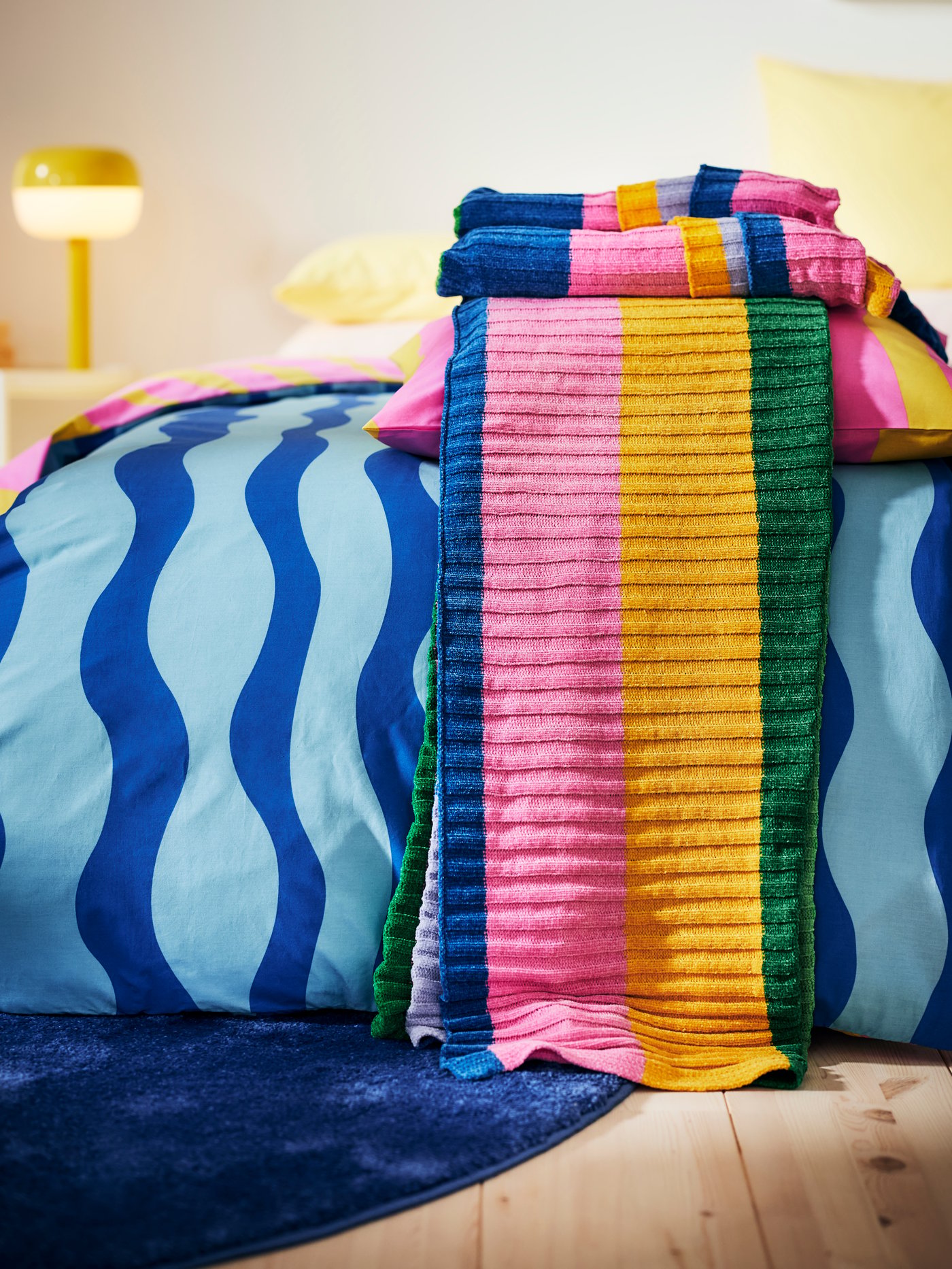 Im Vordergrund die FJÄLLTRIFT Kuscheldecke. Diese liegt passend zum SOMMARVICKER Bettwäscheset auf dem Bett schön aufdekoriert.