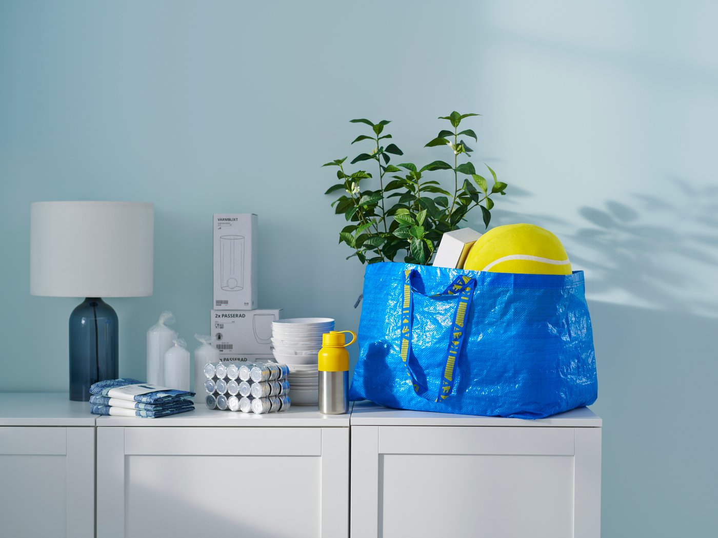 En blå taske fyldt med indkøb fra IKEA på en skænk ved siden af IKEA-produkter.