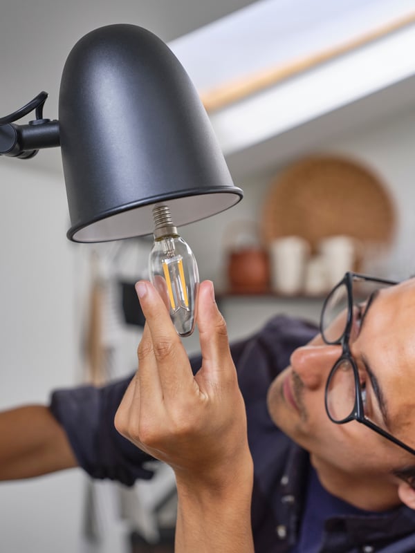 Person installing an energy-efficient light bulb in a lamp.				